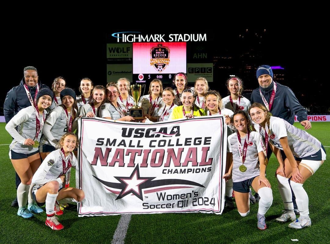women's soccer team and coaches pose with championship banner